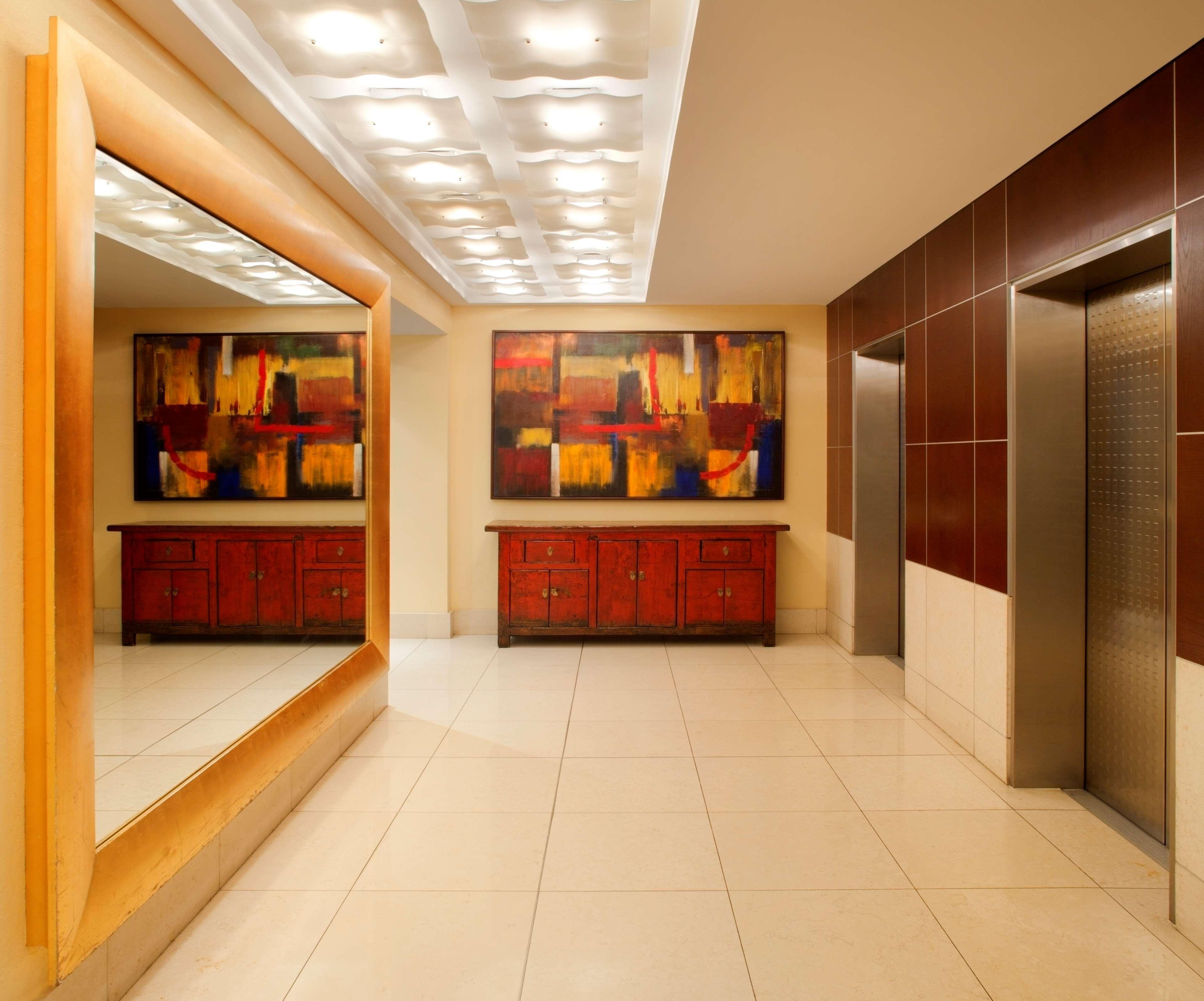 Radisson Blu Plaza Hotel Σίδνεϊ Εξωτερικό φωτογραφία The photo shows a modern lobby area with a polished, sleek design. On the left side, there is a large mirror framed in wood, reflecting part of the space. The wall opposite features a pair of elevators, which are metallic and set within a contemporar