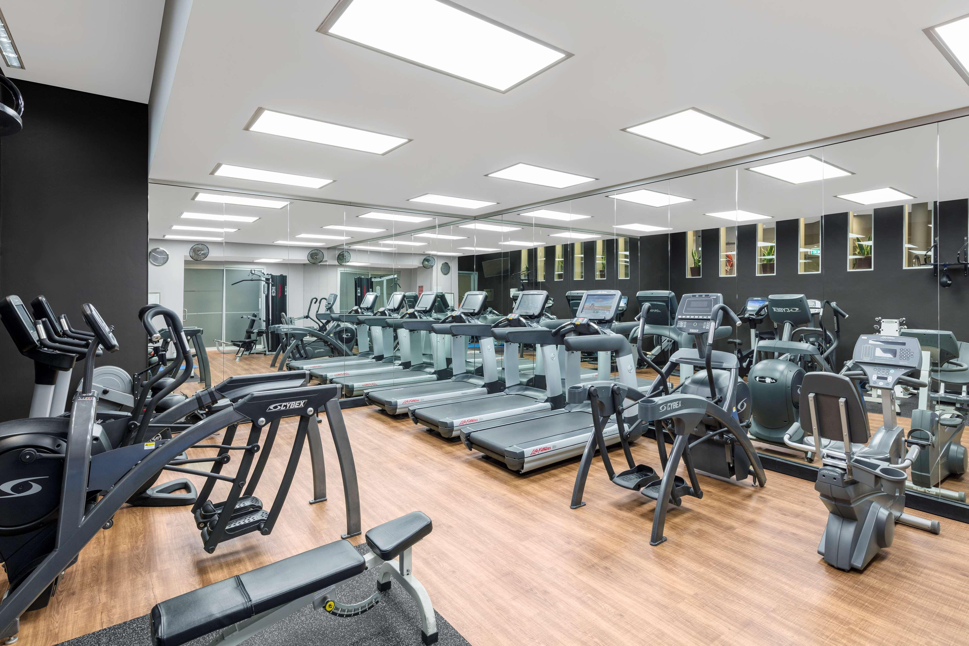 Radisson Blu Plaza Hotel Σίδνεϊ Εξωτερικό φωτογραφία The photo shows a modern gym interior. It features various exercise machines, including several treadmills and some strength-training equipment. The flooring is wooden, which gives the space a warm feel, and the walls are painted dark, contrasting wi