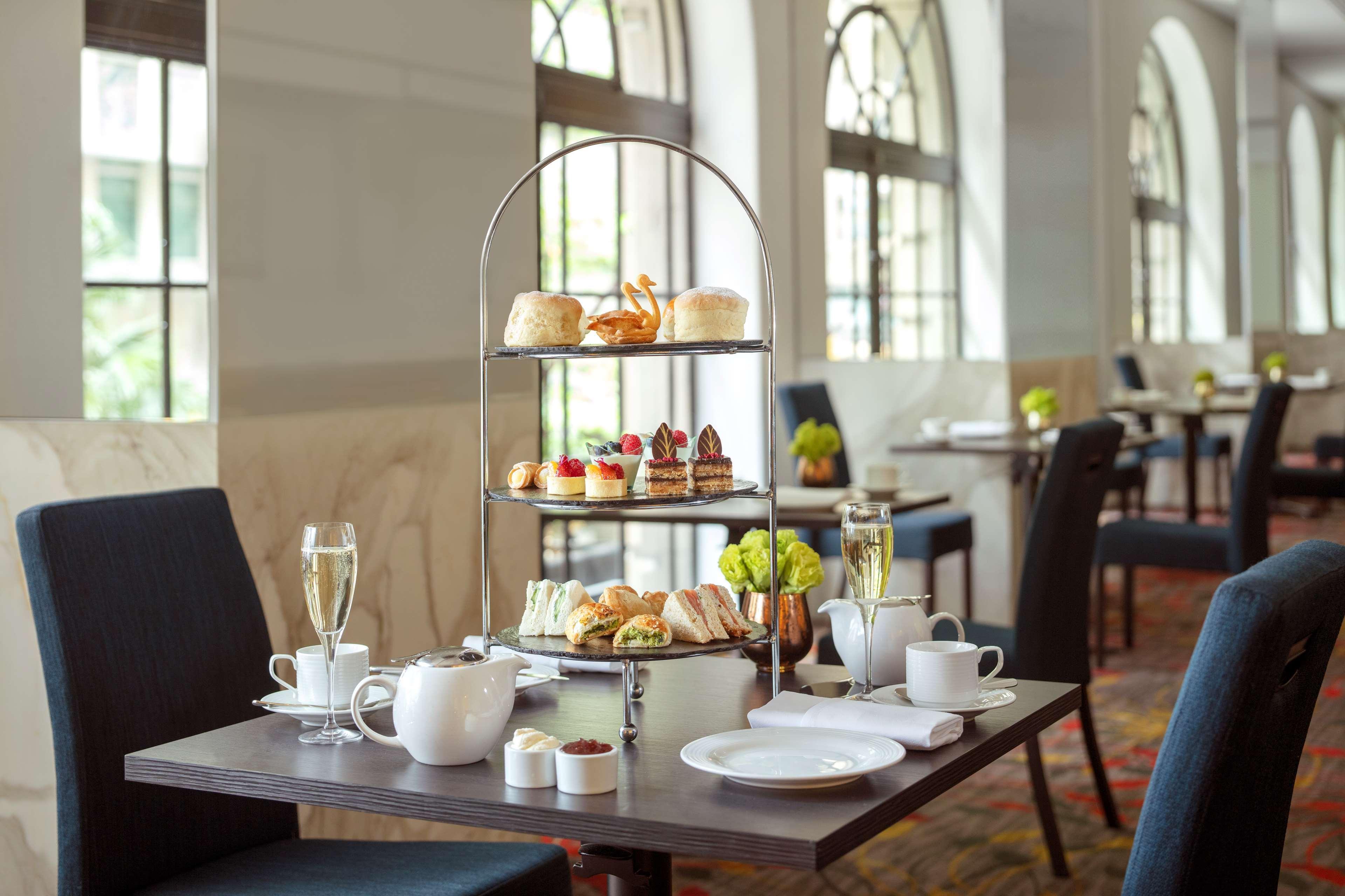 Radisson Blu Plaza Hotel Σίδνεϊ Εξωτερικό φωτογραφία The photo depicts a beautifully arranged afternoon tea setup on a table in a cozy dining area. In the center, there is a three-tiered stand displaying a variety of treats, including pastries, scones, and finger sandwiches. The table has a teapot, tea