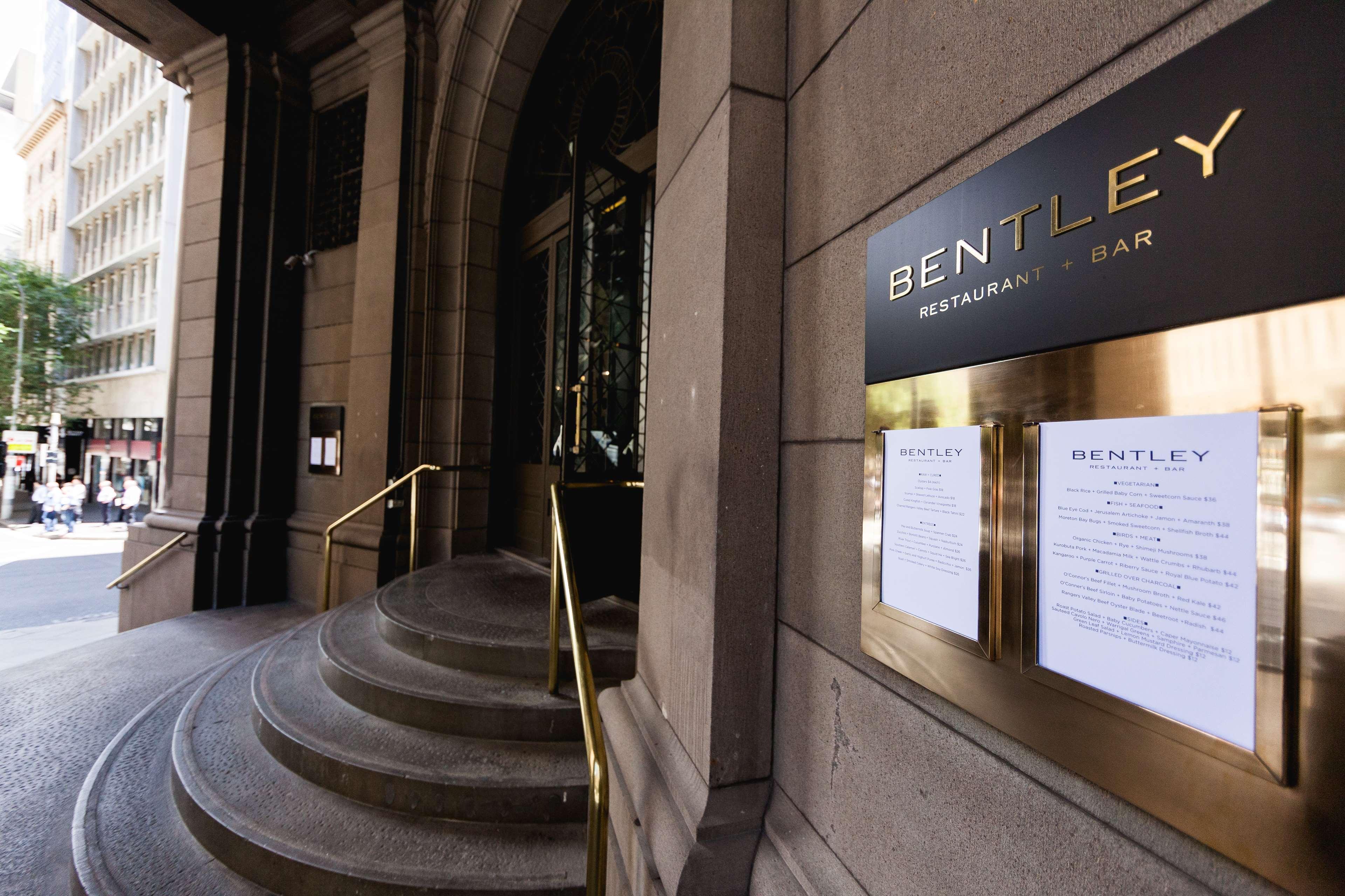 Radisson Blu Plaza Hotel Σίδνεϊ Εξωτερικό φωτογραφία The photo shows the entrance of a restaurant and bar named "Bentley." The exterior features a prominent sign with the restaurant's name in gold letters. There is a set of elegant stone steps leading up to the entrance, which is framed by architectura