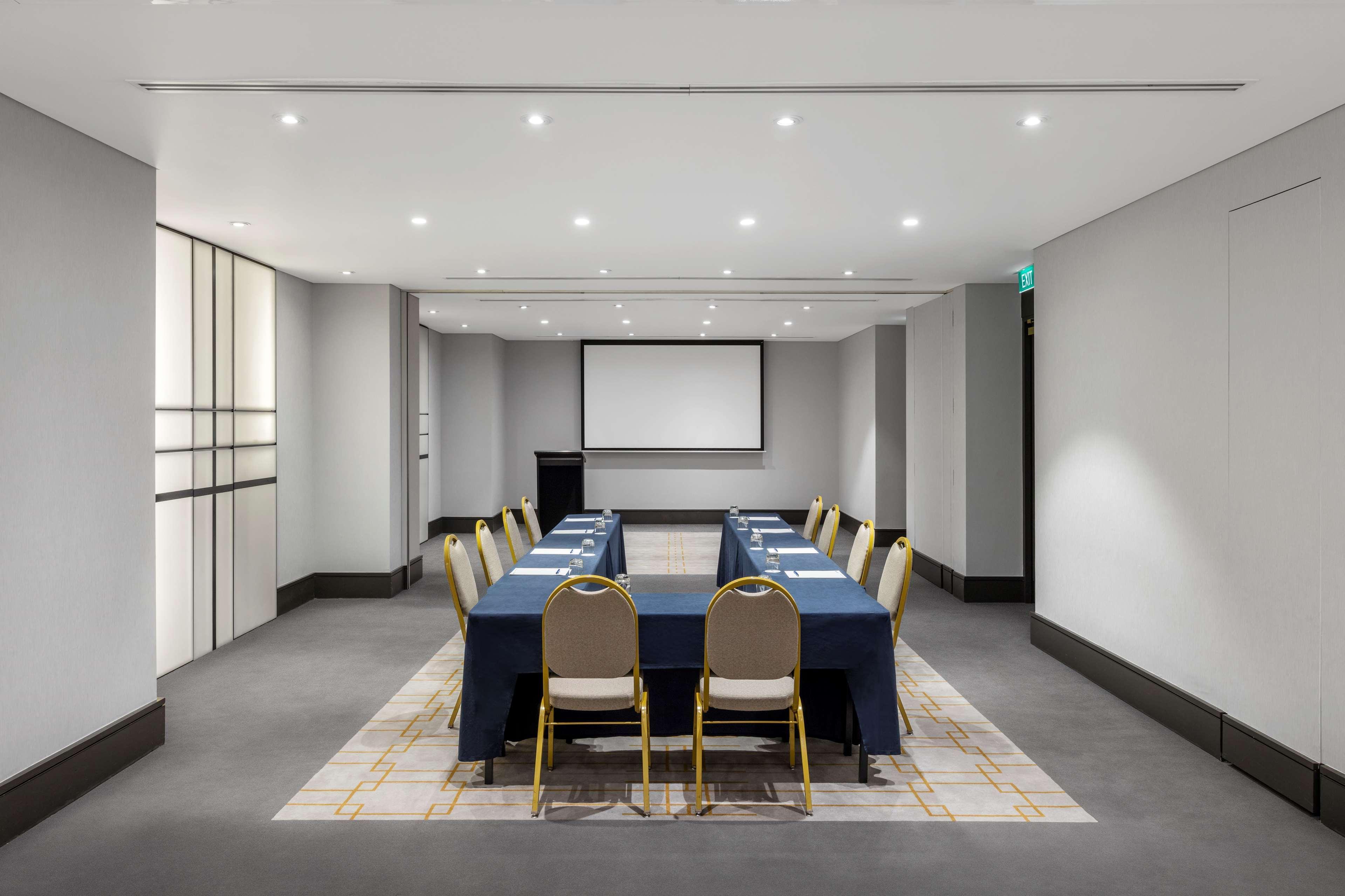 Radisson Blu Plaza Hotel Σίδνεϊ Εξωτερικό φωτογραφία The photo shows a modern conference room. The space is well-lit, featuring overhead lights and a neutral color palette. In the center, there is a long rectangular table covered with a navy blue tablecloth, surrounded by several chairs with beige upho