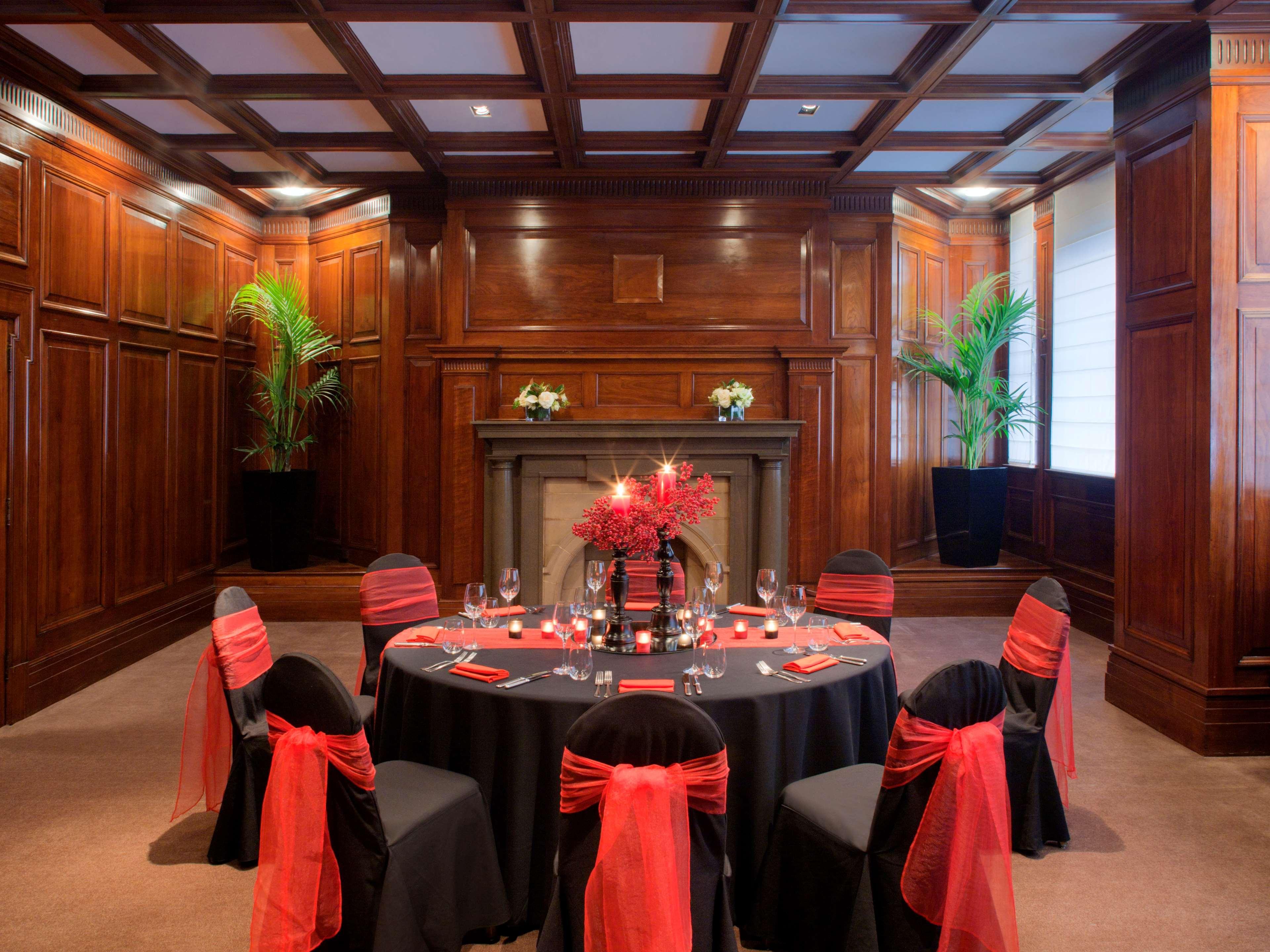 Radisson Blu Plaza Hotel Σίδνεϊ Εξωτερικό φωτογραφία The photo shows an elegant dining setup in a richly decorated room. The walls are made of dark wood paneling, contributing to a warm and sophisticated atmosphere. In the center, there is a round table covered with a black tablecloth, surrounded by ch