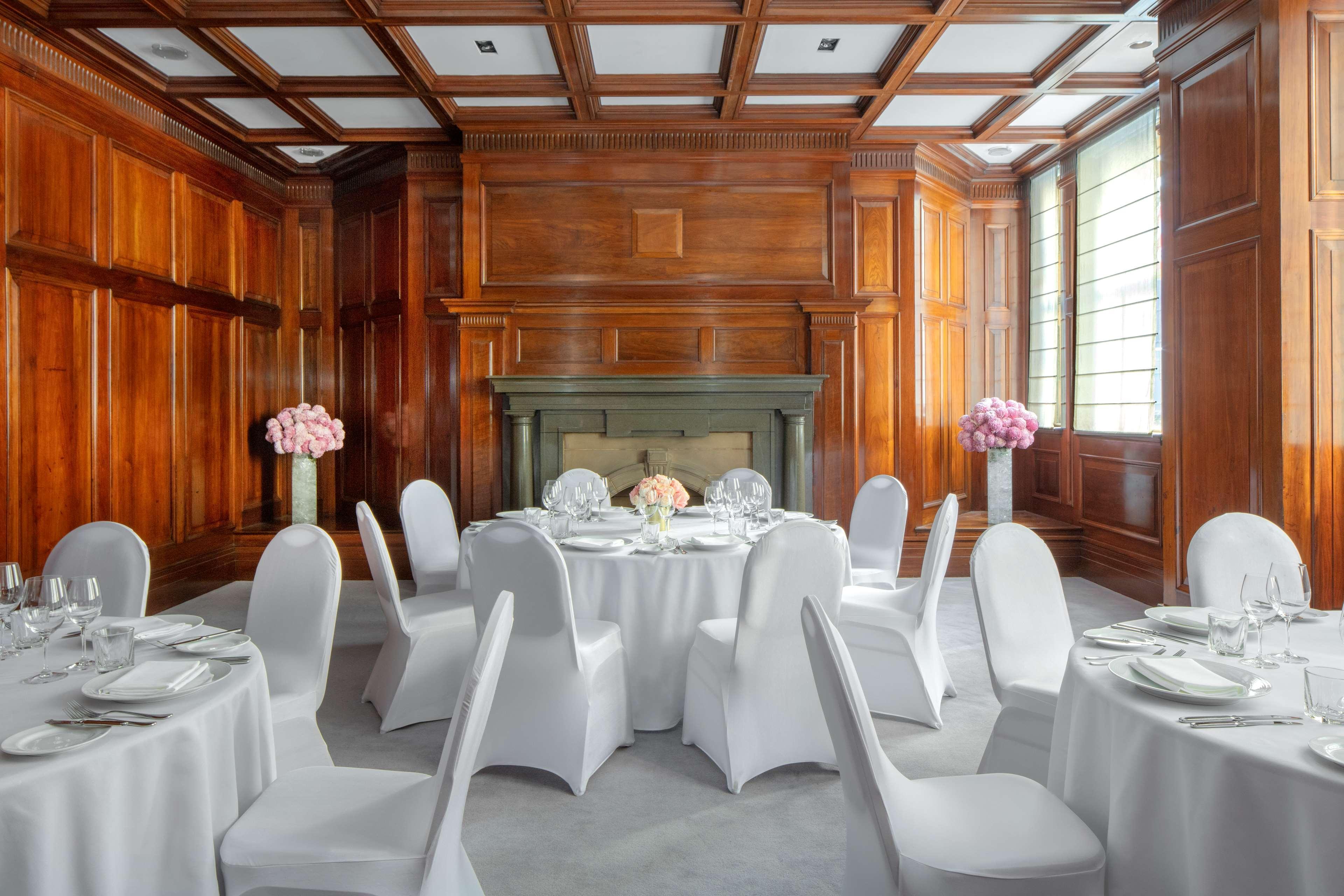 Radisson Blu Plaza Hotel Σίδνεϊ Εξωτερικό φωτογραφία The photo shows an elegant dining room with a classic design. The room features rich wooden paneling on the walls and a detailed coffered ceiling. In the center, there are round tables covered with white tablecloths, accompanied by white chairs that 