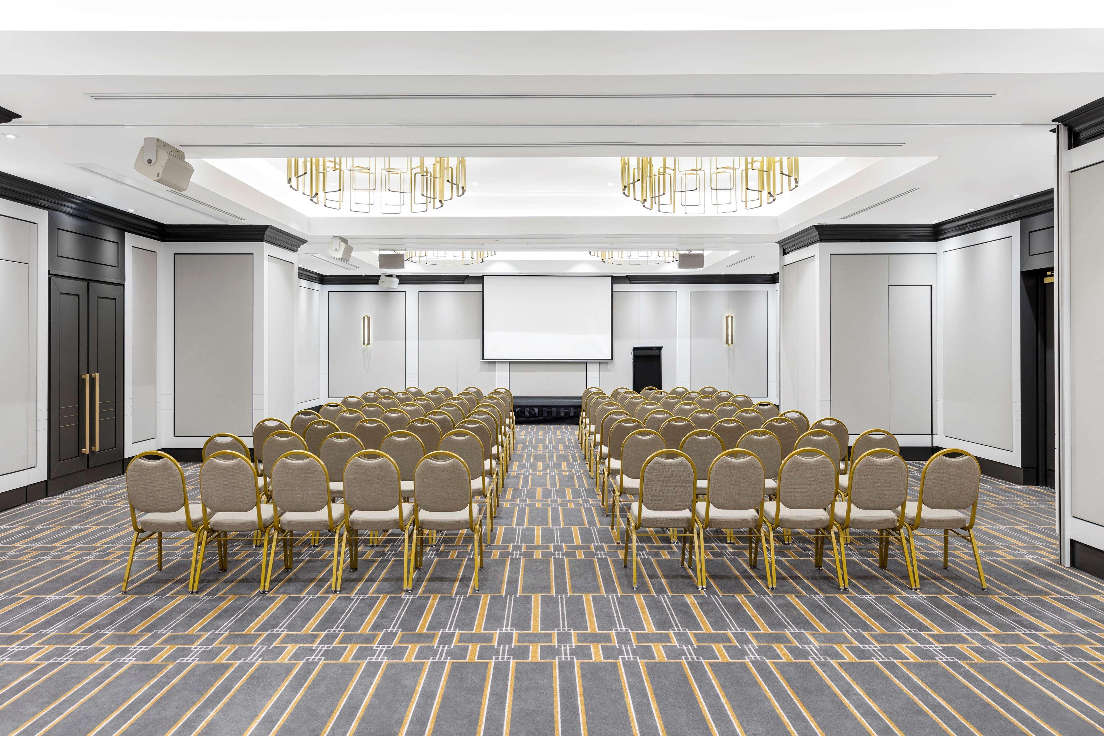 Radisson Blu Plaza Hotel Σίδνεϊ Εξωτερικό φωτογραφία The photo shows a spacious conference room set up for an event. There are multiple rows of beige chairs arranged in front of a screen at the front of the room. The room features modern decor, with a clean and elegant design. The ceiling has decorativ