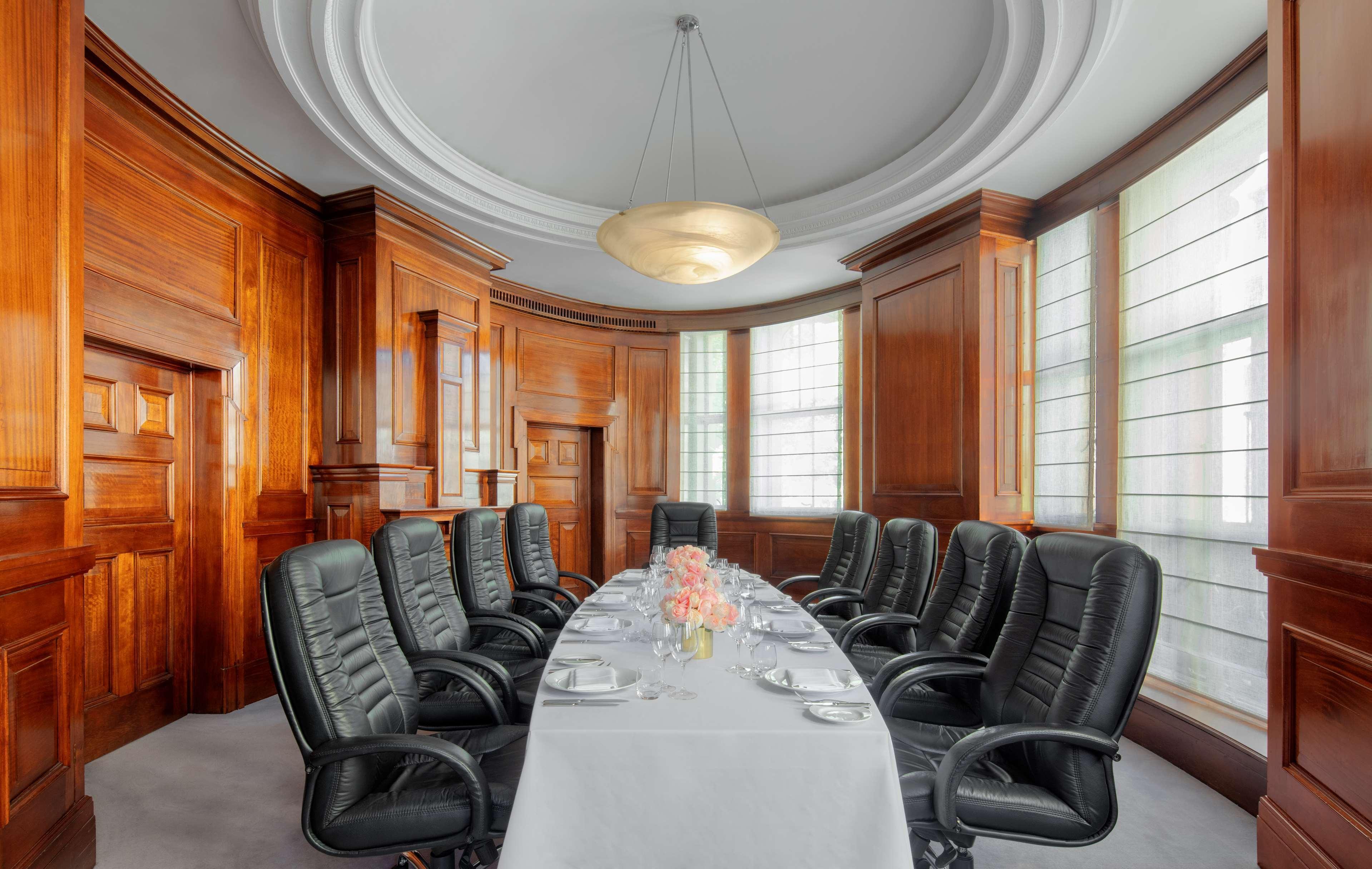 Radisson Blu Plaza Hotel Σίδνεϊ Εξωτερικό φωτογραφία The photo depicts a stylish conference room featuring a long, oval table set with elegant tableware. There are several black leather executive chairs arranged around the table. The room has rich wooden paneling, giving it a classic and sophisticated 