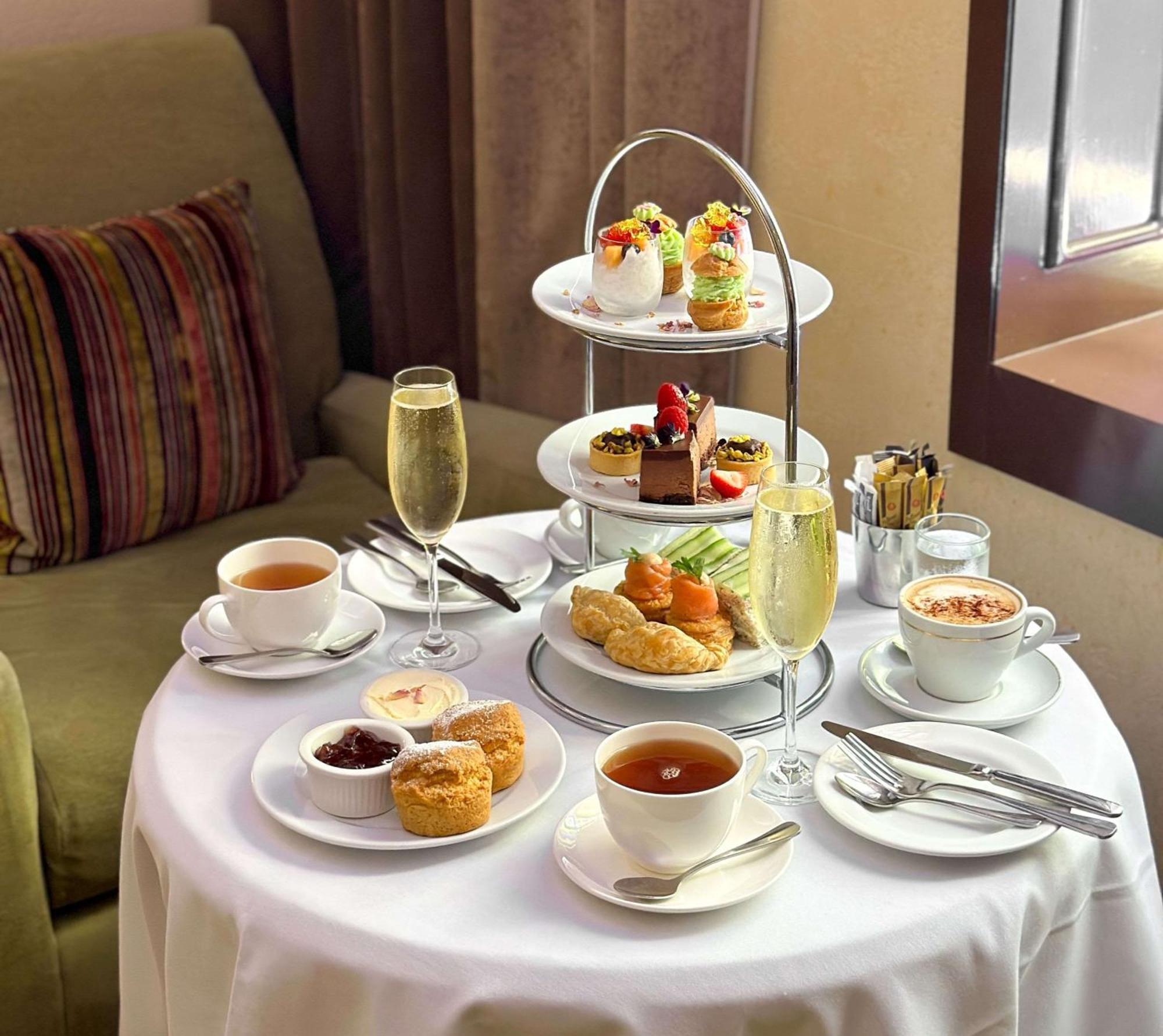 Radisson Blu Plaza Hotel Σίδνεϊ Εξωτερικό φωτογραφία The photo depicts a beautifully arranged table set for afternoon tea. At the center, there is a three-tiered stand filled with a variety of desserts, including small cakes, pastries, and fruit-topped treats. Surrounding the stand are cups of tea and 
